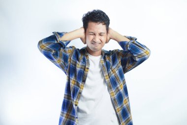 Yetişkin Asyalı adam çaresizce bağırırken eliyle kulaklarını kapatıyor.