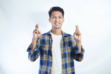 Tişört giyen Asyalı adam, mutlu yüz ifadesiyle çapraz işaret yapıyor.