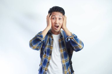 20 'li yaşlarda, sıradan kıyafetler giyen, sırt çantalı, elinde yanağıyla beyaz arka plandaki kameraya bakan genç bir Asyalı. Lise üniversite konsepti