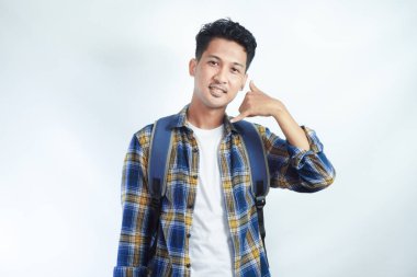 Sırt çantalı heyecanlı genç Asyalı öğrenci beyaz arka planda izole edilmiş işaret işareti yapıyor. Lise üniversite konsepti eğitimi