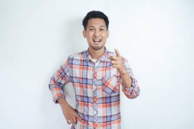 Yetişkin Asyalı adam kameraya bakıyor ve coşkulu bir ifadeyle işaret ediyor.