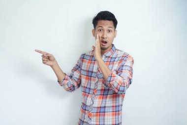 Yetişkin Asyalı adam dedikodu yapıyor ve birini işaret ediyor.