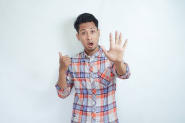 Yetişkin Asyalı adam endişeli bir ifadeyle dur işareti yapıyor ve sağ tarafı işaret ediyor.