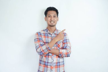 Yetişkin Asyalı adam, sağ eli sol tarafı işaret ederken mutlu gülümsüyor.