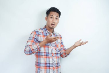 Yetişkin bir Asyalı iki eli de sağ tarafı gösteren şok olmuş bir ifade sergiliyor.