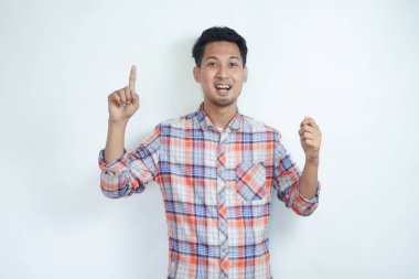 Yetişkin Asyalı bir adam elinde bir şey tutarken heyecanlı bir ifadeyle yukarı bakıyor.