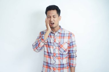 Yetişkin bir Asyalı çenesine acı ifadesiyle dokunuyor.