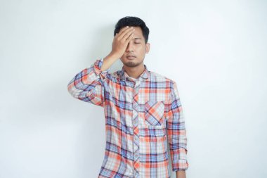 Ekose gömlek giyen bitkin Asyalı genç bir adam beyaz arka planda izole edilmiş bir baş ağrısı ile elini alnına koydu. insanlar yaşam tarzı konsepti