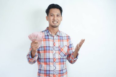 Yetişkin Asyalı adam elinde para tutarken kameraya gülümsüyor.