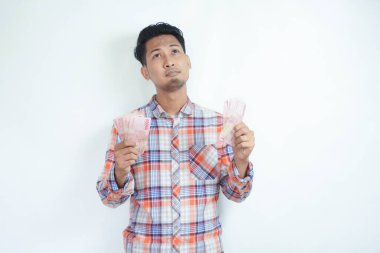 Yetişkin Asyalı adam kağıt parasını sayarken bir şey düşünüyor.