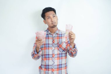 Yetişkin Asyalı adam kağıt parasını sayarken bir şey düşünüyor.