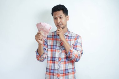 Yetişkin Asyalı adam Endonezya 'da kağıt para tutarken düşünce hareketi yapıyor.