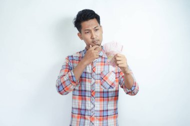 Yetişkin Asyalı adam Endonezya 'da kağıt para tutarken düşünce hareketi yapıyor.