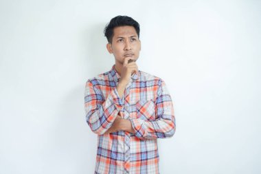 Flanel tişört giyen yetişkin bir Asyalı düşünme hareketi gösteriyor.