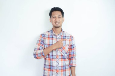 Yetişkin Asyalı adam, sağ eli sol tarafı işaret ederken mutlu gülümsüyor.