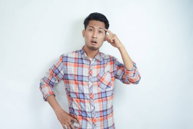 Yetişkin bir Asyalı, şakağını göstererek kafasını karıştırıyor.