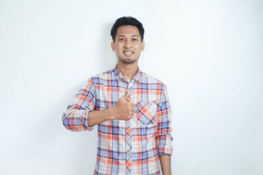 Yetişkin Asyalı adam gülümsüyor ve kameraya başparmağını kaldırıyor.