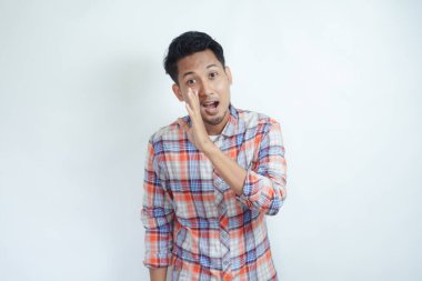 Yetişkin bir Asyalı beyaz arka planda fısıldayarak hareket ediyor.