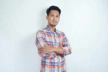 Asyalı adam kollarını kavuşturarak gülümsüyor.