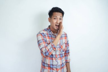 Yetişkin bir Asyalı beyaz arka planda fısıldayarak hareket ediyor.