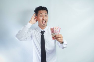 Yetişkin Asyalı adam elinde kağıt para tutarken gülen yüz ifadesi gösteriyor.