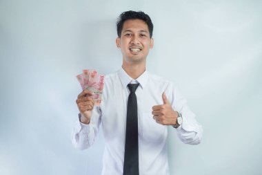 Asian businessman smiling and give thumb up while holding money clipart
