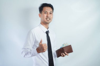 Asyalı işadamı gülümsüyor ve elinde para tutarken başparmağını bırakıyor.