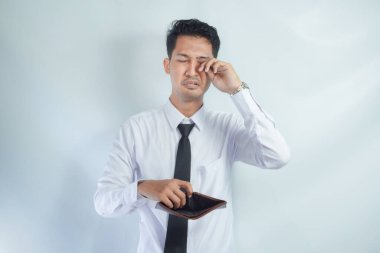 Adult Asian man showing his empty wallet with worried expression clipart