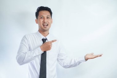 Yetişkin Asyalı adam sağ eli açık sol avucunu işaret ederek gülümsüyor.