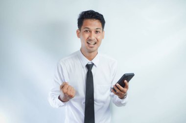 Yetişkin Asyalı adam cep telefonunu tutarken kameraya bakıyor.