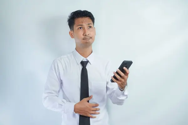 businessman holding stomach and cellphone thinking about ordering food online. online food ordering concept