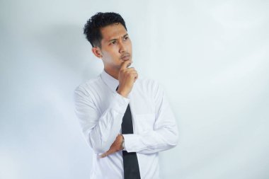Beyaz gömlek giyen genç Asyalı adam düşünce hareketi gösteriyor.
