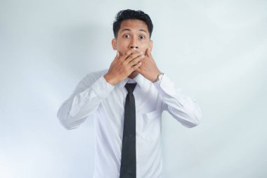 Dehşete düşmüş genç Asyalı iş adamının suratını örten ve yüzünde korkmuş bir ifadeyle kameraya bakan, işteki başarısızlıktan korkan fotoğrafı.