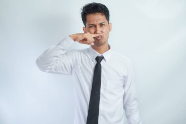 Asian businessman standing while covering his nose. Bad smell concept. Isolated on white clipart