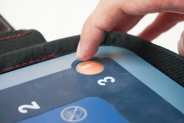 Kalp krizi geçiren bir hastaya elektrik şoku vermek için AED 'nin şok düğmesine bas.