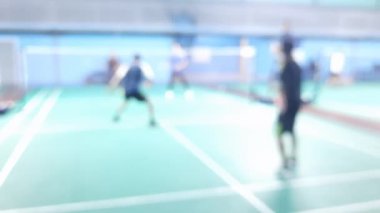İnsanlar kapalı alanda oynamayı öğrenirken badminton salonunun bulanık çevre görüntüsü.
