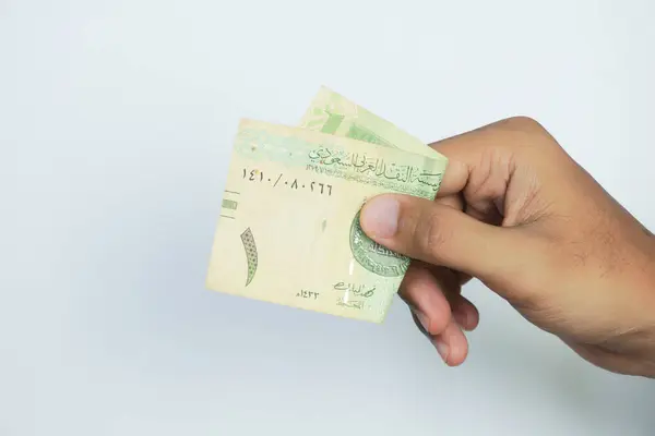 stock image hand holding 1 Riyal Saudi Arabia money , on a white background.