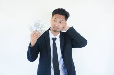 Stüdyoda dolar tutan genç Asyalı adam kafasının arkasına dokunuyor, düşünüyor ve bir seçim yapıyor..