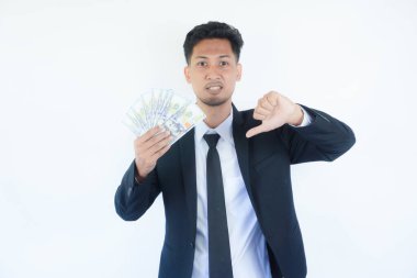 Asyalı yakışıklı bir adam elinde dolarlarla kızgın bir yüz, olumsuz işaretler baş parmakları aşağıda, reddedilme konsepti.