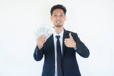 Büyük şans. Asyalı neşeli iş adamı, elinde nakit para tutarken, Beyaz Stüdyo Arkaplan 'ın önünde poz veriyor. Kâr ve Mali Başarı,