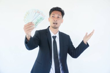 Heyecanlı Asyalı 20 'li yaşlarda takım elbiseli genç bir iş adamı nakit para hayranı banknotlar halinde el ele dağıtıyor.
