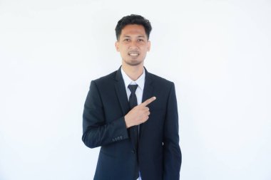 Asyalı işadamı kameraya gülümsüyor. Bir eli sol tarafı işaret ediyor.