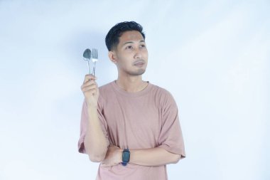 Çekici, neşeli bir adamın portresi çatal kaşıkla elele tutuşup, tenha beyaz bir arka plan bekliyor.