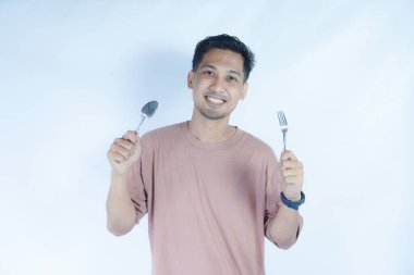 Çekici, neşeli bir adamın portresi çatal kaşıkla elele tutuşup, tenha beyaz bir arka plan bekliyor.