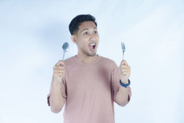 Çekici, neşeli bir adamın portresi çatal kaşıkla elele tutuşup, tenha beyaz bir arka plan bekliyor.