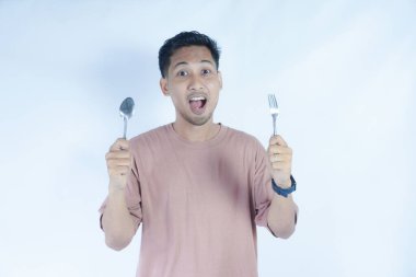 Çekici, neşeli bir adamın portresi çatal kaşıkla elele tutuşup, tenha beyaz bir arka plan bekliyor.