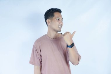 Pembe tişörtlü Asyalı bir adam, sanki beklenmedik bir şey fark ediyormuş gibi şaşırmış ve meraklı bir ifadeyle onu işaret ediyor. Açık mavi arka plan onun animasyonunu vurguluyor.