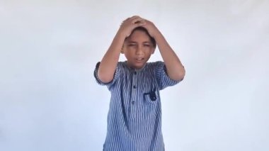 Asyalı sevimli bir çocuk elleri kafasında günlük kıyafetler giyiyor, stres yüzünden baş ağrısı çekiyor. migren ağrısı.