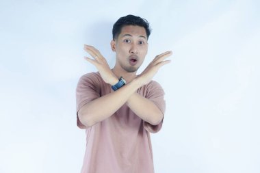 Pembe tişörtlü bir adam, tasvip etmeyen bir ifadeyle kollarını kavuşturur. Sanki 