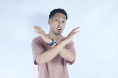 Pembe tişörtlü bir adam, tasvip etmeyen bir ifadeyle kollarını kavuşturur. Sanki 